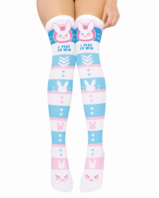 Over-the-knee socks with a pastel blue, pink, and white bunny-themed pattern and the text 'I PLAY TO WIN' on the upper leg, shown on a model's legs against a white background.