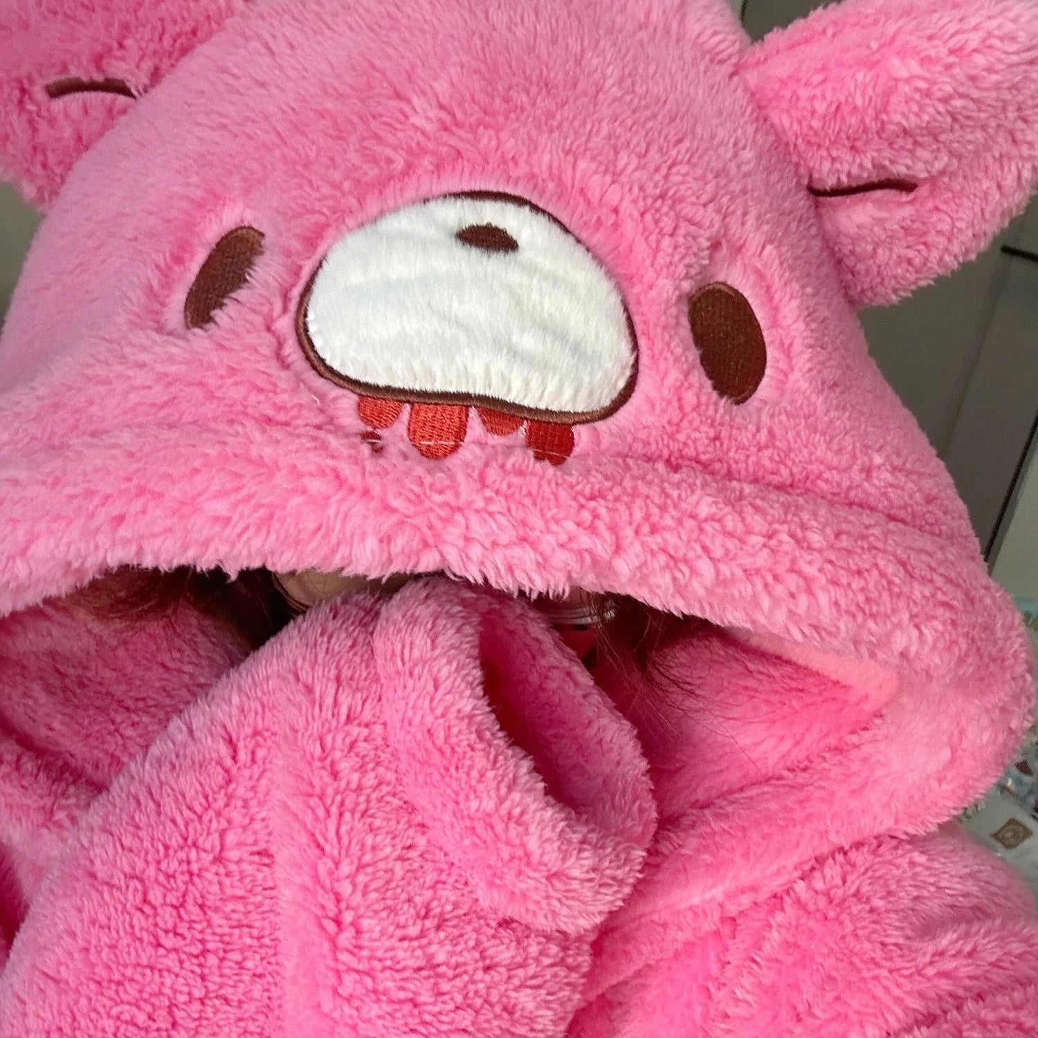 Close-up of the plush pink Gloomy Bear hood featuring 3D ears and embroidered face with red drip details 
