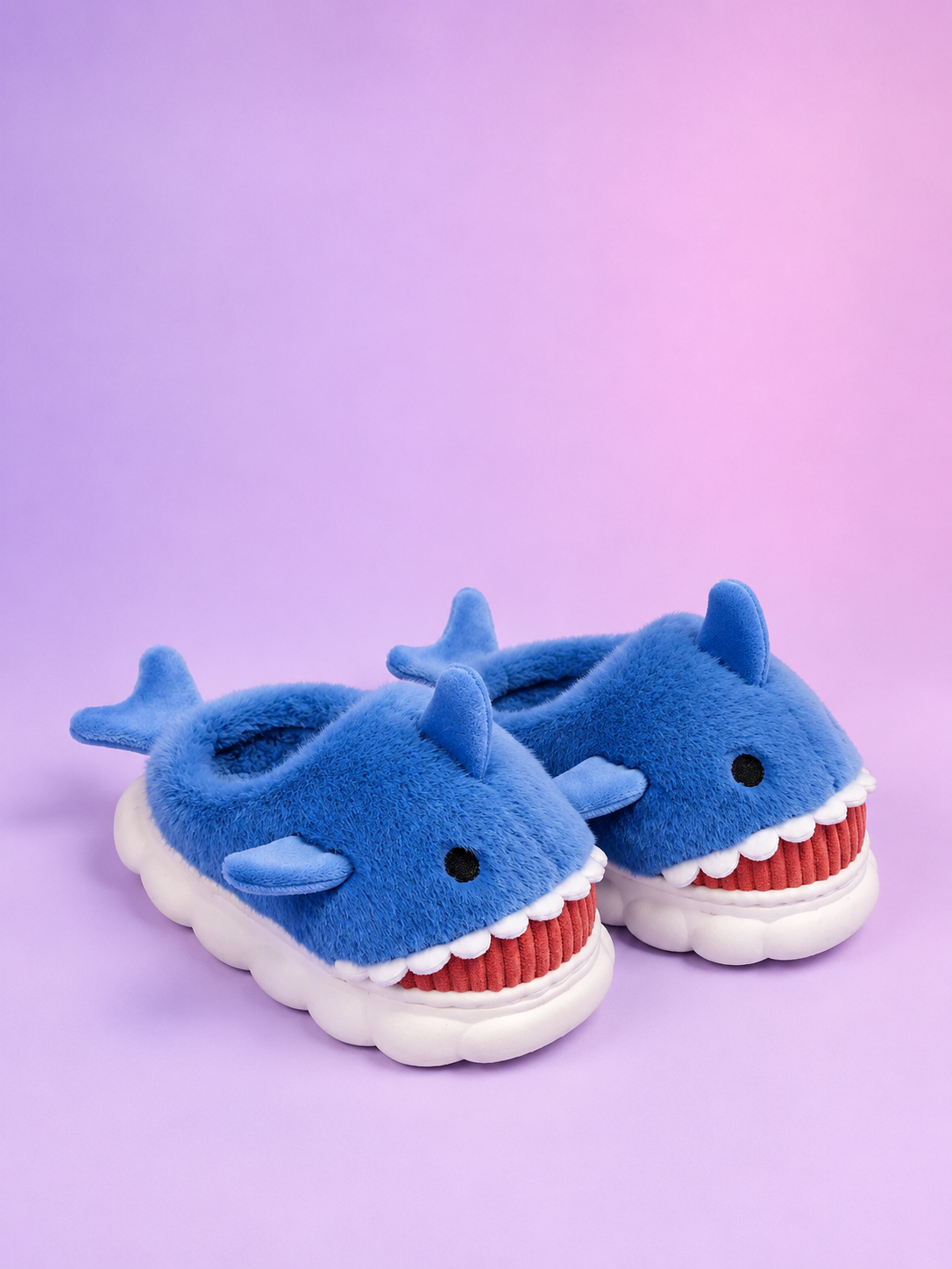Blue shark-themed slippers with white soles on a purple background