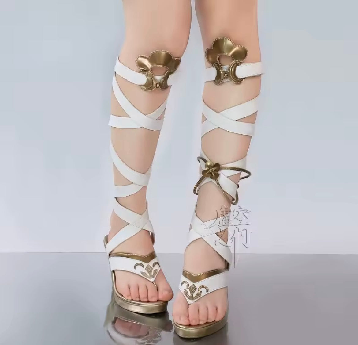 White sandals with gold straps and decorative elements on a white background