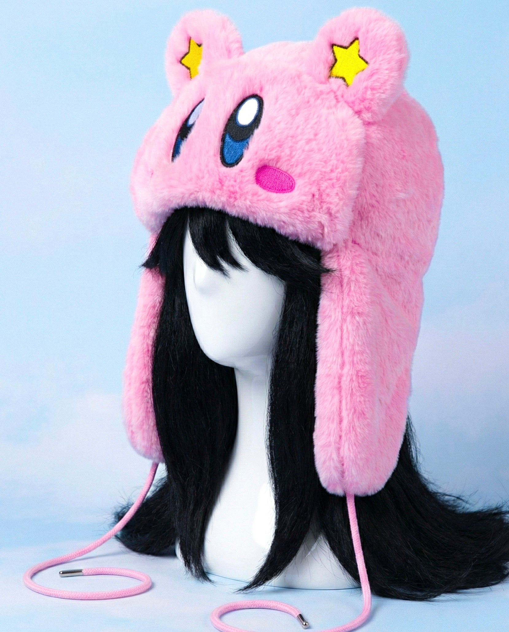 view of Kirby inspired pink fluffy cosplay hat with embroidered face details and long ear flaps, kawaii anime winter accessory