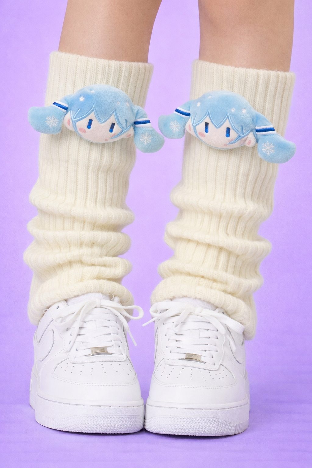 White socks with blue character designs worn with white sneakers on a purple background