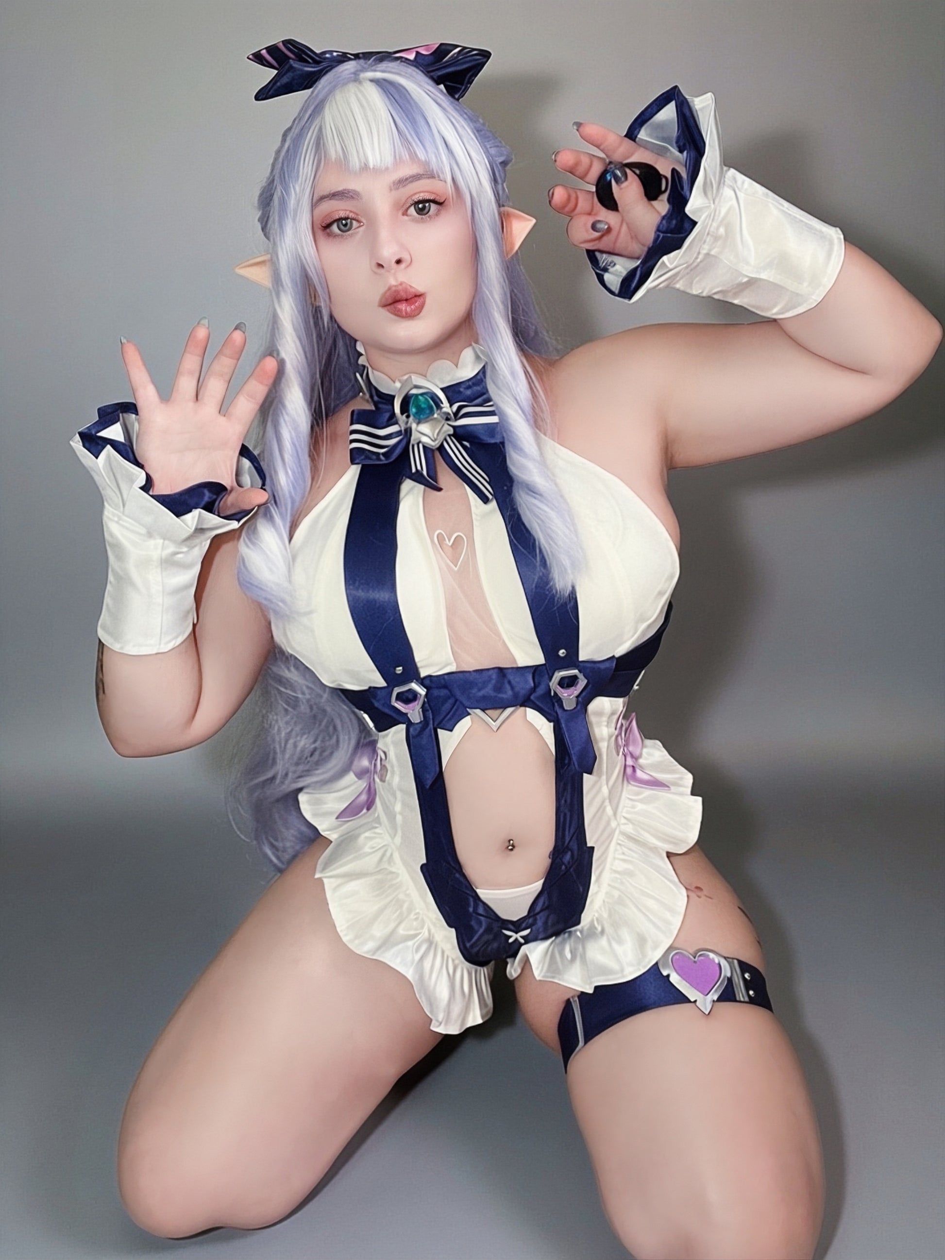 Shiq Sama modelling the Vivian cosplay costume from Zenless Zone Zero in a seated pose, showing the full costume detailing