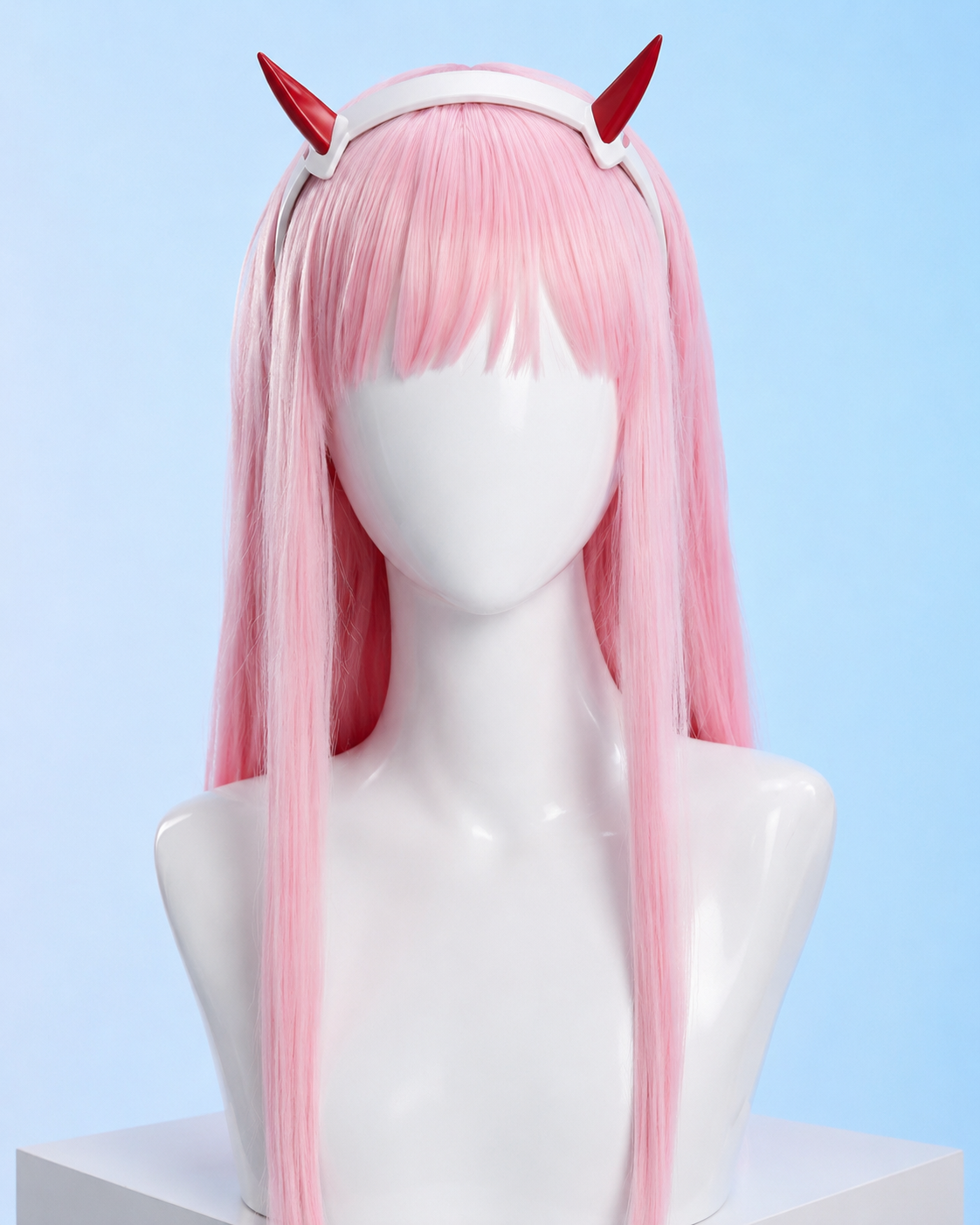 Pink wig with red devil horns on a mannequin head against a light blue background